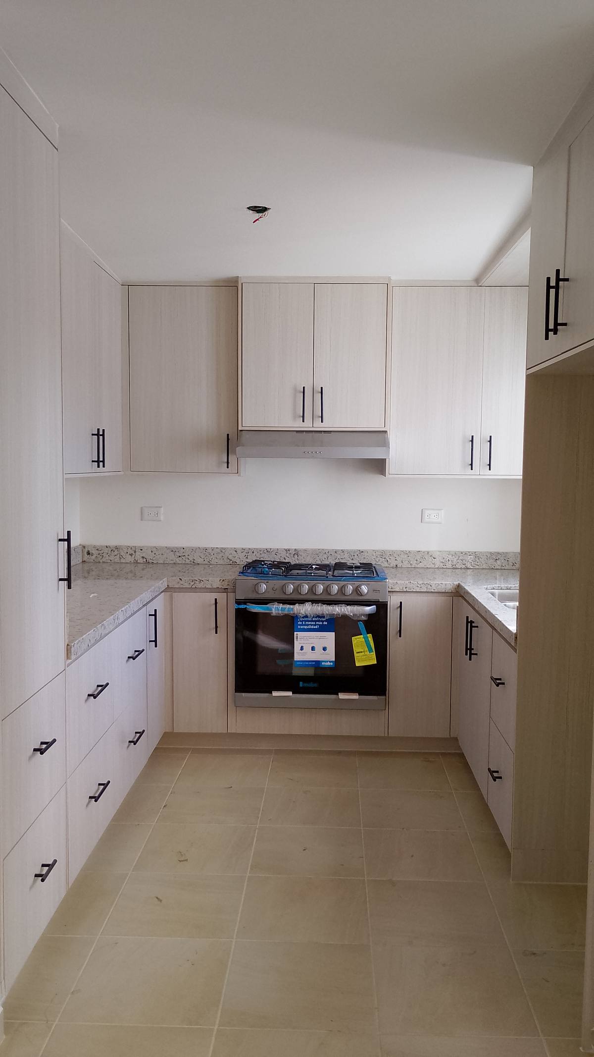 Cocina integral en lino claro con herrajes negros y granito